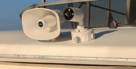 Installed white bow camera and round junction box beside the horn